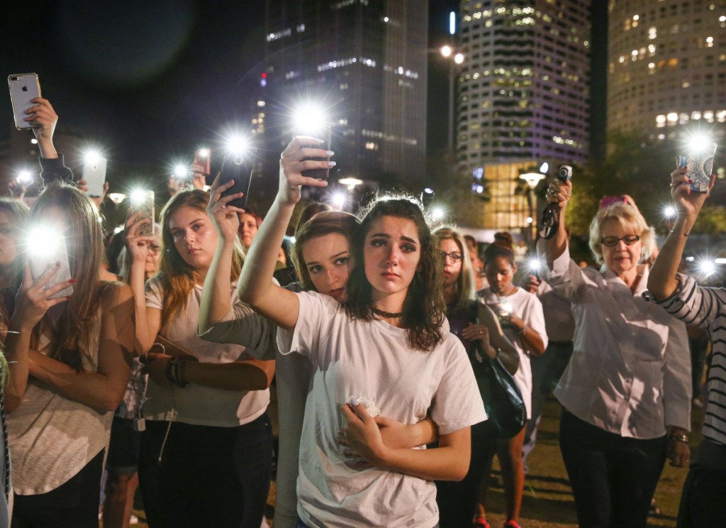 Mary Claire Foley, center left, 16, embraces Ariana Skafidas, 16, students at Henry B. Plant High School at Curtis Hixon Park in downtown Tampa, Fla., on Monday as they raise their lights during a vigil to honor victims of last week's shooting at Marjory Stoneman Douglas High School in Parkland, Fla.