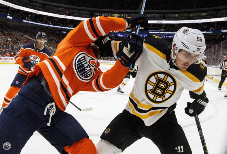 Boston Bruins' Nick Holden and Edmonton Oilers' Adam Larsson  battle in the corner during the third period of the game on Tuesday in Edmonton.