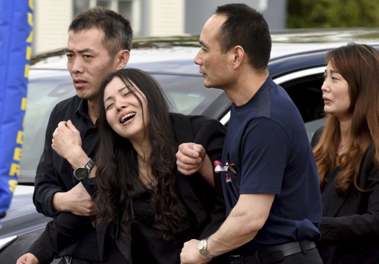Peter Wang's mother, Hui, cries as she is helped into a waiting car with her family after the memorial service for her 15-year-old son at Kraeer Funeral Home in Coral Springs, Fla., on Tuesday. Peter Wang was among the victims in the massacre at Marjory Stoneman Douglas High School in Parkland, Fla., last week.