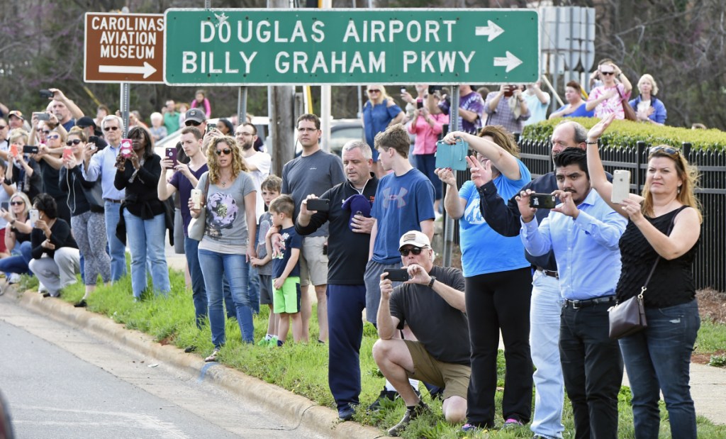 People take photos as the hearse carrying the body of Billy Graham drives toward Charlotte, N.C., on Saturday.