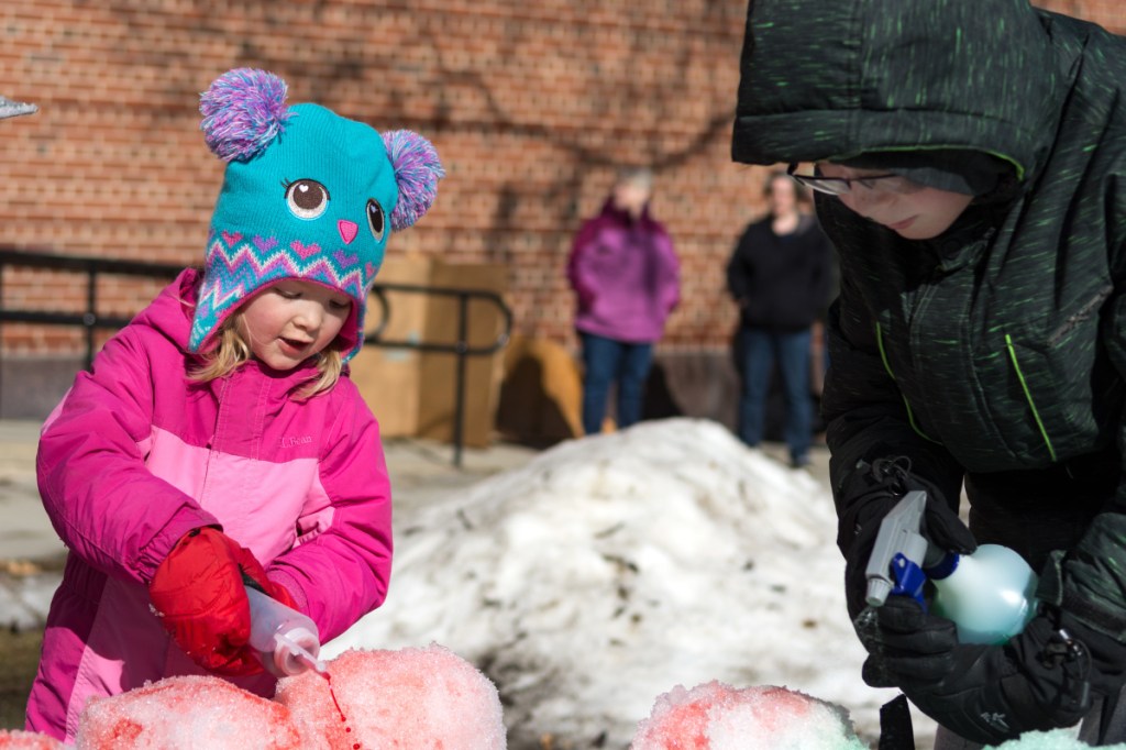 Abigail Downie and her brother Jayden Downie, of Oakland, add color to a snow castle they carved out of a block of snow. The pair filled a large cardboard box with snow, packed it down, removed the box and then sculpted the castle Saturday afternoon in Castonguay Square in Waterville.