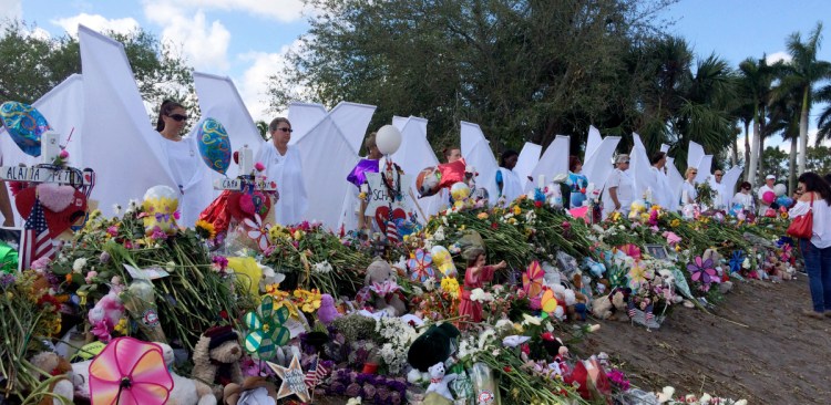 Seventeen people dressed as angels stand Sunday at the memorial outside Marjory Stoneman Douglas High School in Parkland, Fla., for those killed in the shooting on Feb. 14. "We want the survivors to know angels are looking over them and protecting them," organizer Terry Decarlo said.