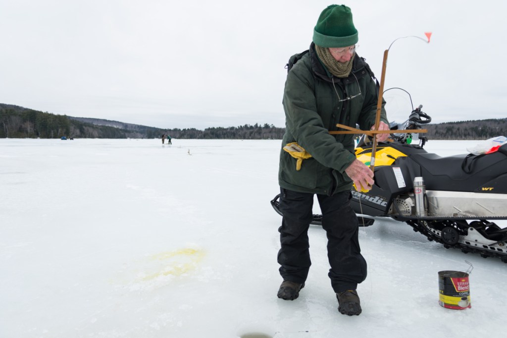 Dallas Folk, one of the organizers of Sports Unlimited of Maine, demonstrates the springing of a trap, while helping to set up for Hooked on Fishing on Berry Pond in Wayne on Sunday.