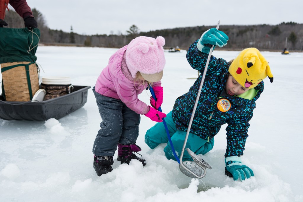 Jac-Lynne, 4, left, and Elyse Hinkley, 8, scoop ice out of a hole on Berry Pond as they take part in Hooked on Fishing in Wayne on Sunday.
