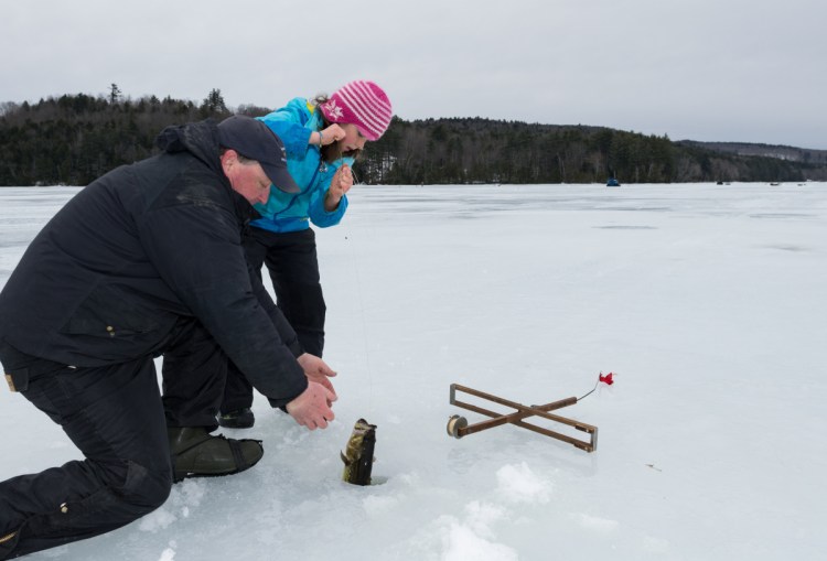Abby St. Clair, 9, of Winthrop receives help from a family friend Sunday on Berry Pond, while pulling in a 2-pound largemouth bass. The youth fishing derby was hosted by Sports Unlimited of Maine in Wayne.