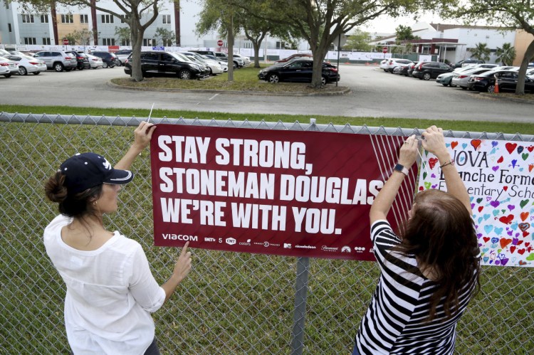 Volunteers hang banners around the perimeter of Marjory Stoneman High School in Parkland, Fla., to welcome back students who will be returning to school Wednesday two weeks after the mass shooting that killed 17 students and staff. (Susan Stocker/South Florida Sun-Sentinel via AP)