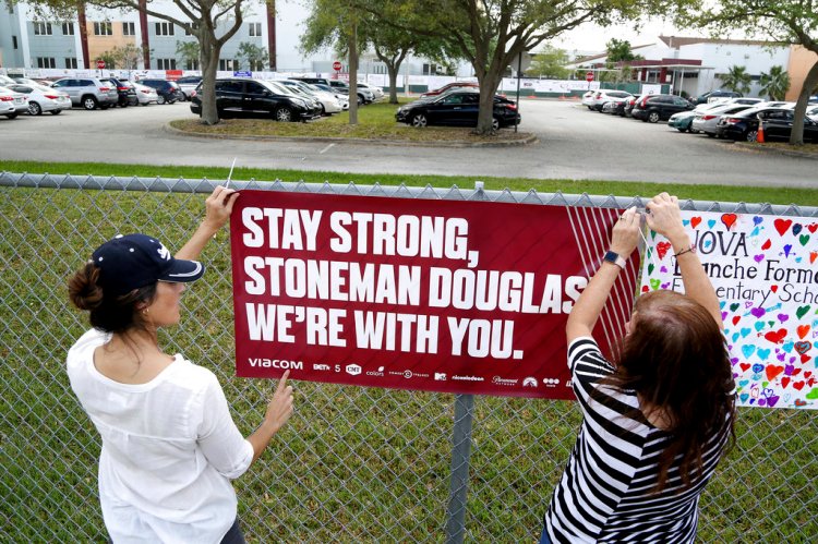 Volunteers hang banners at Marjory Stoneman High School in Parkland, Fla., to welcome back students who will be returning to school Wednesday two weeks after the mass shooting that killed 17 students and staff. 