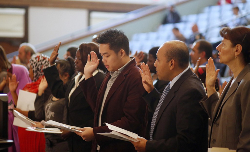New U.S. citizens are naturalized in a 2013 ceremony in Portland. A reader says immigrants are better off if they work their way to success instead of getting help.