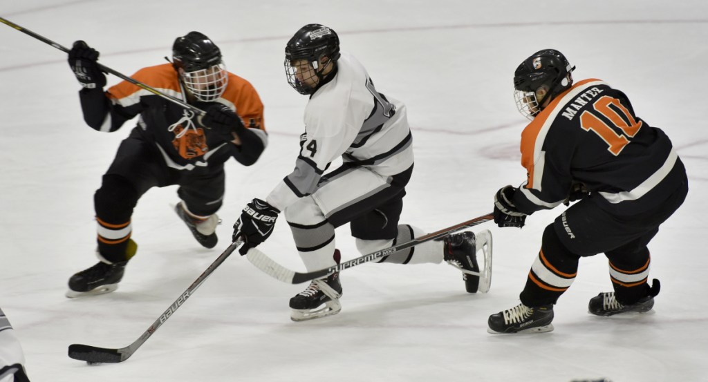 Kennebec's Hunter Brown, middle, skates between Gardiner defenders during a game earlier this season at Colby College.