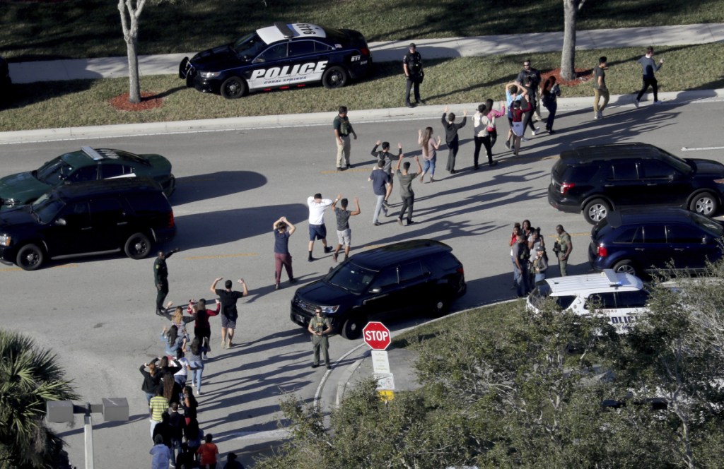 Students hold their hands in the air as police evacuate them from Marjory Stoneman Douglas High School in Parkland, Fla., after a shooter opened fire Feb. 14. 