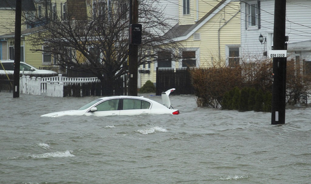 A car along Sea Street is under several feet of water during the storm Friday in Quincy, Mass. A relentless storm pounded the Atlantic coast with hurricane-force winds and sideways-blown rain and snow Friday from North Carolina to Maine.