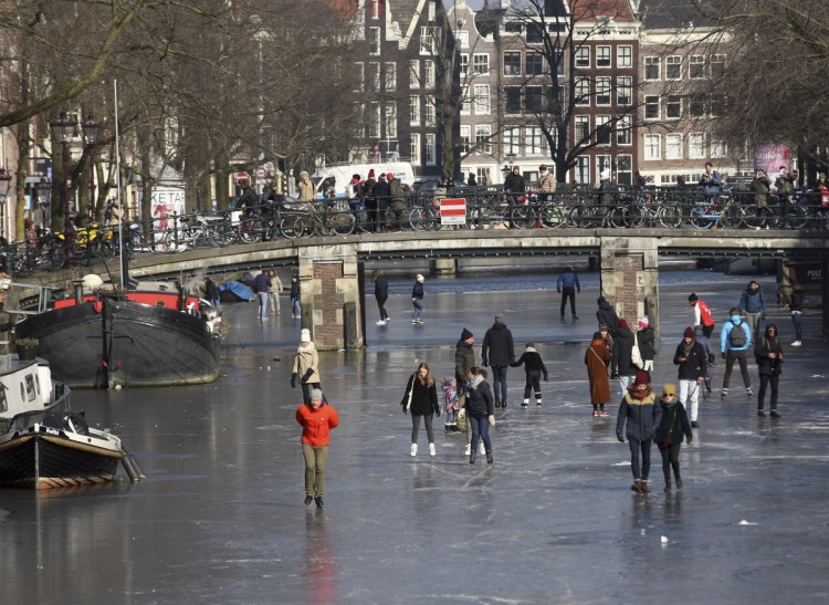 People walk and skate on the frozen Prinsengracht canal in downtown Amsterdam on Friday as cold weather gripping much of Europe hangs on.