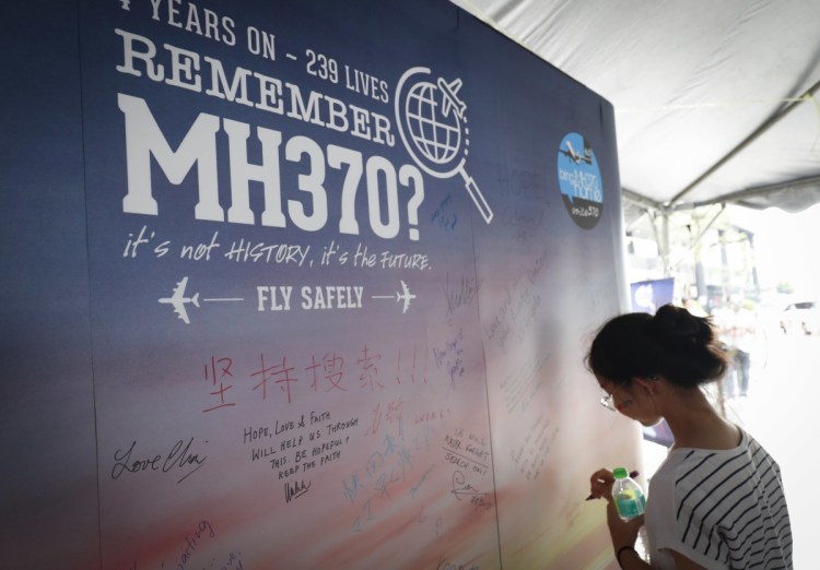 A girl writes a condolence message during the Day of Remembrance for MH370 event in Kuala Lumpur, Malaysia, on Saturday. The remembrance event marked the fourth anniversary of the jet's March 8, 2014, disappearance.