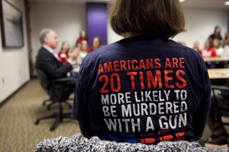 Orna Malone, wearing an anti-gun shirt, listens last week as Sen. Tim Kaine, D-Va., speaks to Moms Demand Action, a group advocating for more gun control, in Richmond, Virginia. The debate over guns has spread across the country since last month's shooting in Parkland, Fla., but many key lawmakers in Congress are choosing to remain silent.
