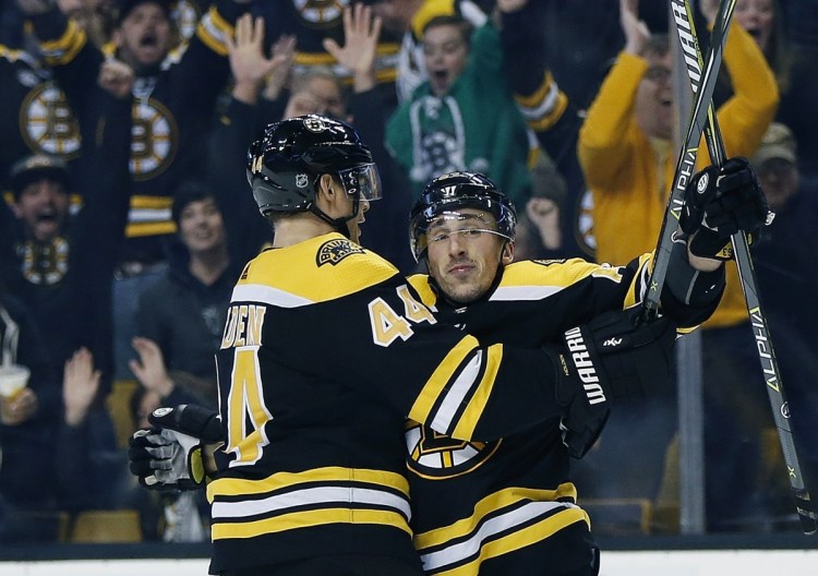 Boston's Brad Marchand, right, celebrates with teammate Nick Holden after scoring the winning goal in overtime of a 2-1 win over Montreal on Saturday in Boston.