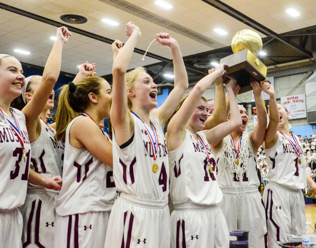 The Monmouth Academy girls' basketball team celebrates with the Gold Ball after beating Houlton to win the Class C state championship on Saturday at the Augusta Civic Center.