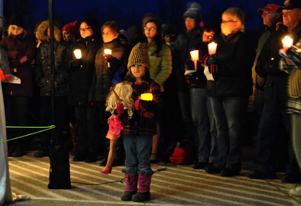 A girl carries a doll during a candlelight vigil Sunday night for 10-year-old Marissa Kennedy in Stockton Springs. Marissa's parents are accused of beating her to death.