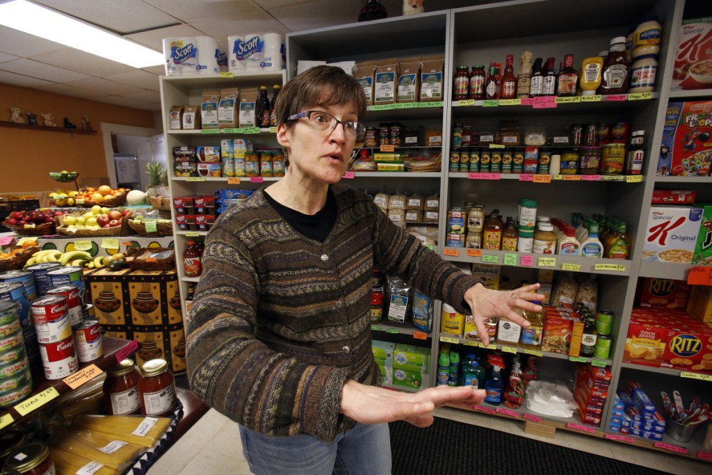 In this Feb. 26, 2018 photo, Dianne Shenk talks to a customer in her Dylamatos Market in Hazelwood, Pa. About a quarter of Shenk's customers pay with benefits from the federal Supplemental Nutrition Assistance Program, so the government's proposal to replace the debit card-type program with a pre-assembled box of shelf-stable goods delivered to recipients concerns her and other grocery operators in poor areas. "These boxes will be full of shelf-stable items, the same things we're being told not to eat," she said. (AP Photo/Gene J. Puskar)
