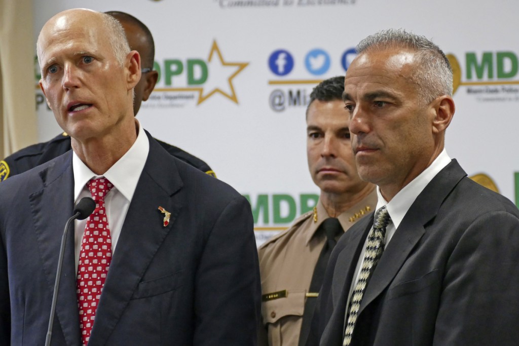 Florida Gov. Rick Scott talks alongside Andrew Pollack, right, whose daughter Meadow was murdered in Parkland, during a news conference in Doral, Fla., on Feb. 27.
