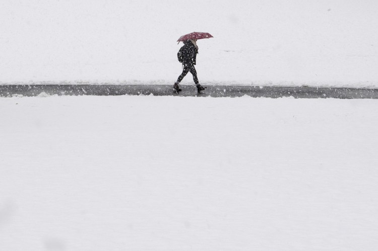 A woman shields herself from the snow with an umbrella as she walks through campus grounds at Swarthmore College in Swarthmore, Pa., on Wednesday.