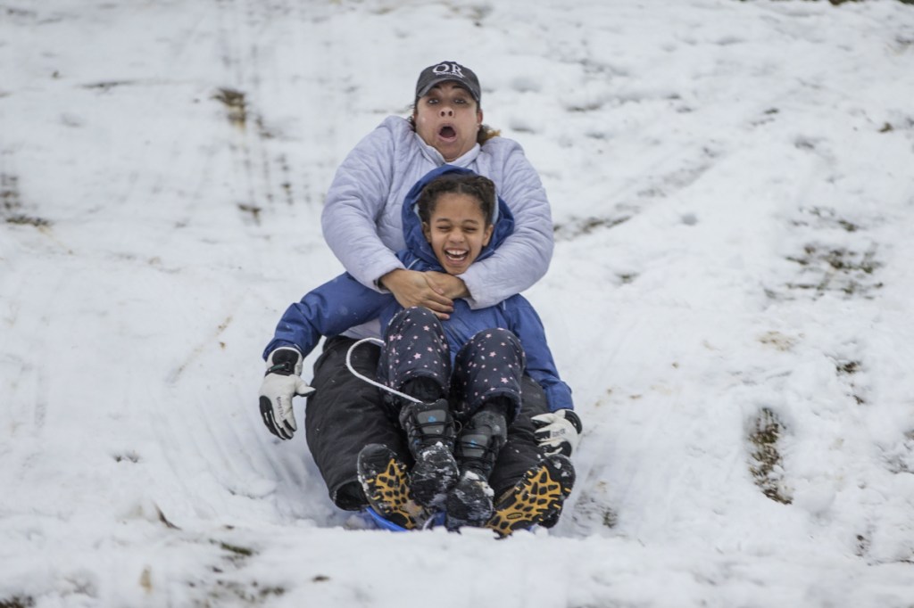 Bridget Mitchell, back, sleds down the Water Tower hill in Chestnut Hill with her daughter, Olivia Mitchell, 9, in Philadelphia on Wednesday.