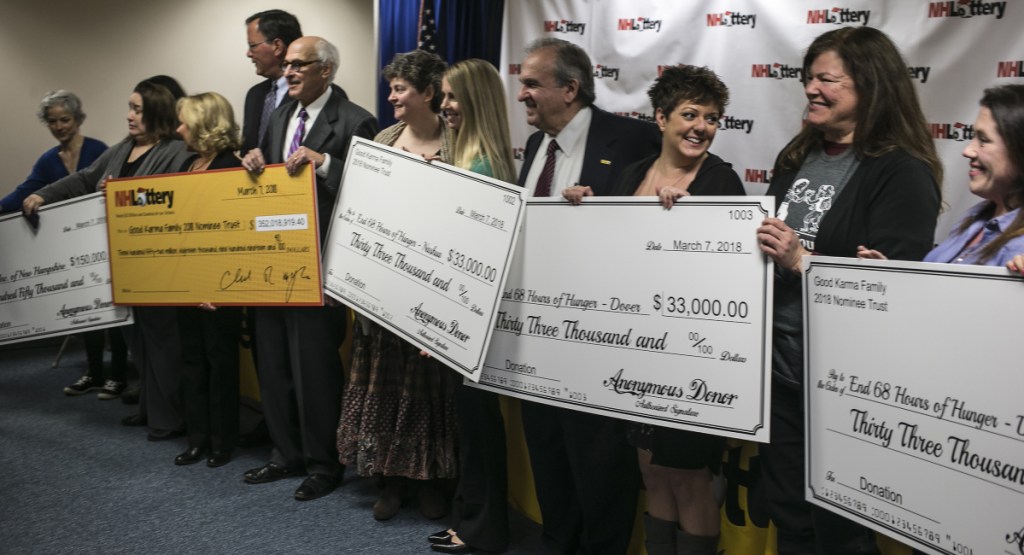 Lottery officials and donation recipients hold up checks Wednesday in Concord, N.H. "I've been here 22 years and never had a day like this," said Cathy Duffy Cullity, CEO of Girls Inc.