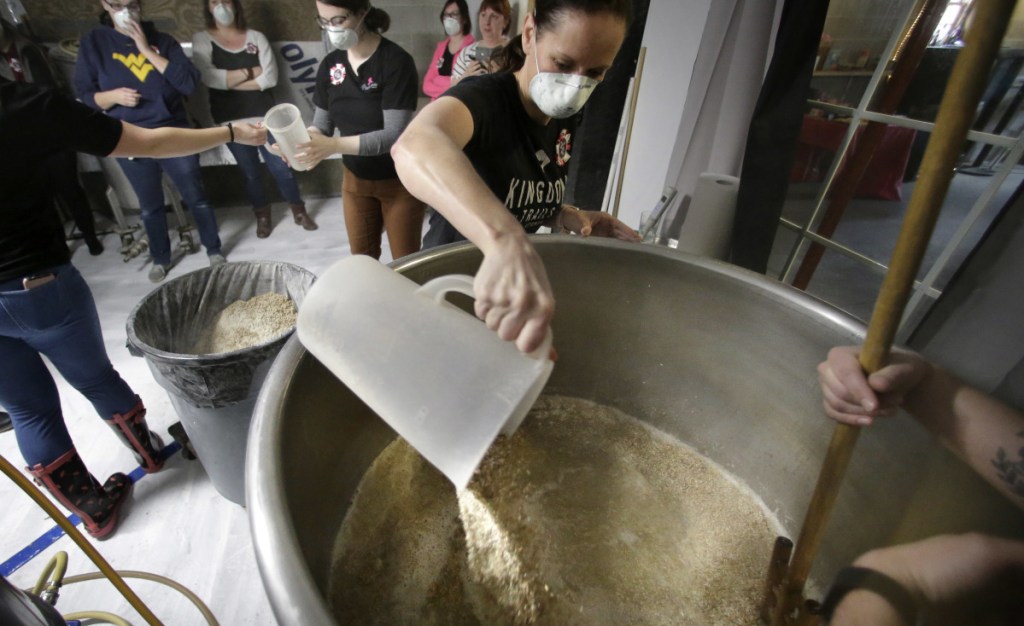 Elizabeth Bove, of Woodstock, Conn., pours grain into a mash mixture at Black Pond Brews brewery in Danielson, Conn.