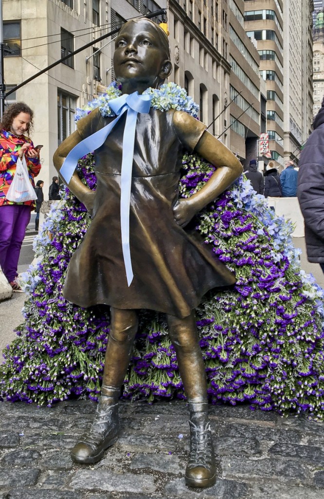 The "Fearless Girl" statue wears a cape of flowers to mark International Women's Day on Thursday.