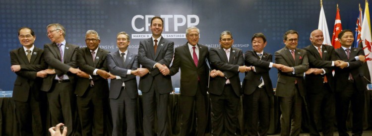 Trade ministers from 11 Pacific Rim nations pose for pictures after signing a sweeping free trade agreement Thursday in Santiago, Chile.