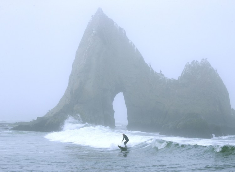 A surfer rides a wave in front of Shark Tooth Rock at Martins Beach in Half Moon Bay, Calif. The beach has become a legal battle between Vinod Khosla and the public.