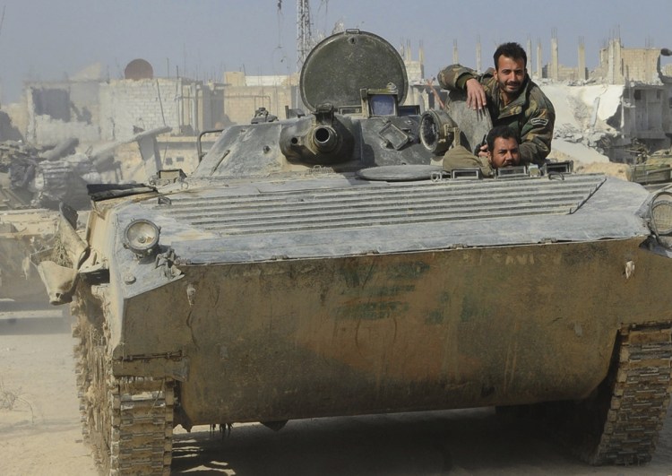 Syrian government soldiers ride in their armored vehicle during a battle against Syrian rebels in eastern Ghouta.
