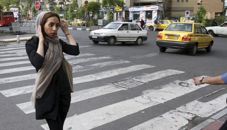 An Iranian woman adjusts her head scarf while crossing a street in Tehran, Iran, in 2016 shortly after officials announced the deployment of 7,000 male and female officers to police the government-mandated dress code.