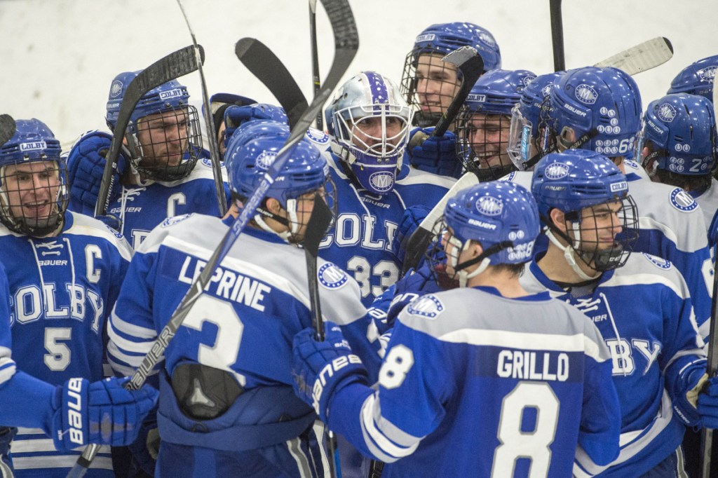 The Colby College hockey team mobs goalie Sean Lawrence after its 4-2 win over the University of New England in the first round of the NCAA Division III men's hockey tournament on Saturday in Biddeford.