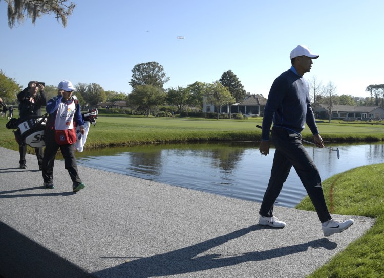 Tiger Woods crosses a bridge to the 16th green during the first round of the Arnold Palmer Invitational in Orlando, Fla. Woods keeps looking better, and shot a 68 Thursday.