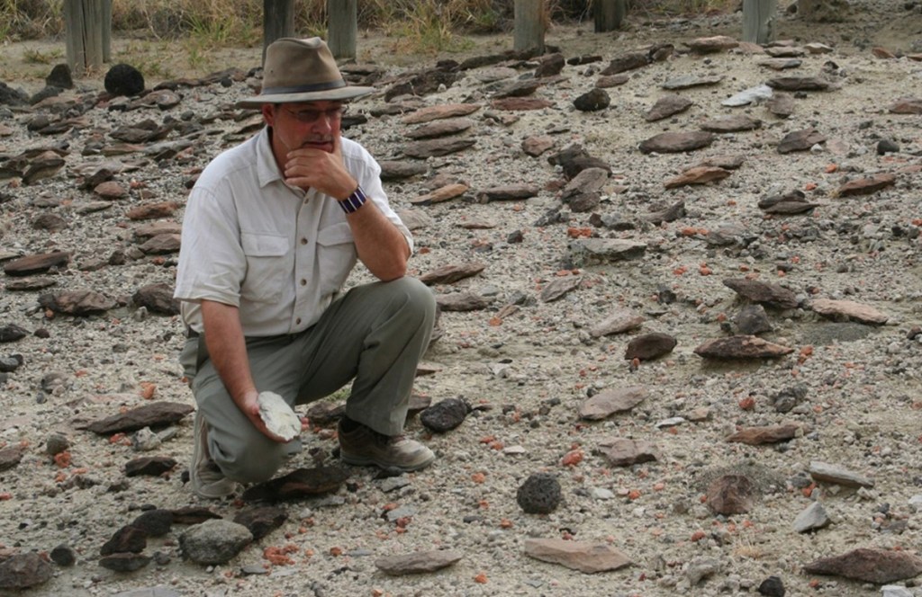 Rick Potts of the Smithsonian surveys an assortment of early stone tools in Kenya's Olorgesaile Basin.
