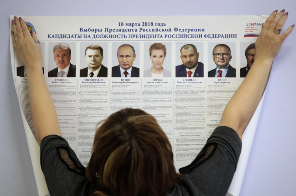 A polling station employee hangs a list of candidates for the 2018 Russian presidential election during preparations for the election at a polling station in St. Petersburg on Friday. On Sunday, presidential elections will be held in Russia. Associated Press/Dmitri Lovetsky