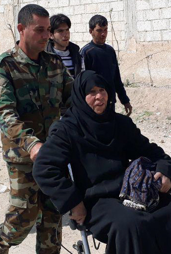 A Syrian soldier helps a woman who fled from fighting near Hamouria in eastern Ghouta on Saturday.