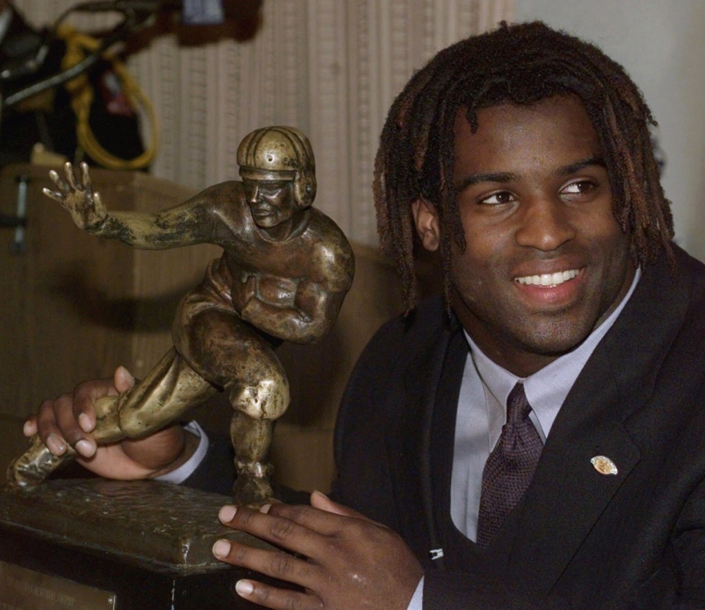 FILE - In this Dec. 12, 1998, file photo, Texas tailback Ricky Williams poses with the Heisman trophy at the Downtown Athletic Club in New York. Williams was selected Friday, Jan. 9, 2015, for for induction to the College Football Hall of Fame. (AP Photo/Suzanne Plunkett, File)