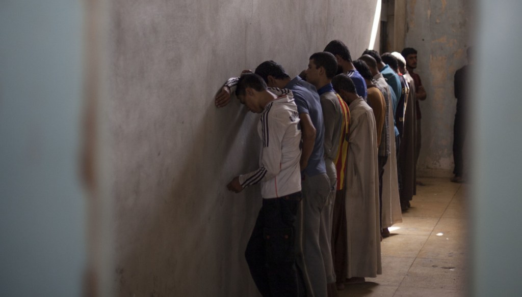 Men from Hawija face a wall to avoid the gaze of security officers deciding if the men have links to the Islamic State.