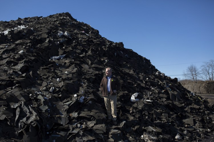 Martin Grohman, on a pile of roof shingles for recycling at the CPRC processing facility in Scarborough.