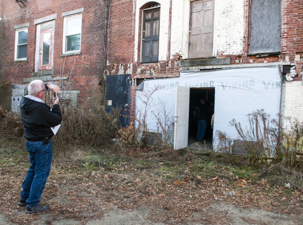 Randall Behm, of Army Corps of Engineers, takes a photo last November of the back walls of 149-167 Water St. in downtown Gardiner as part of an effort to develop strategies to reduce the risk of floods.