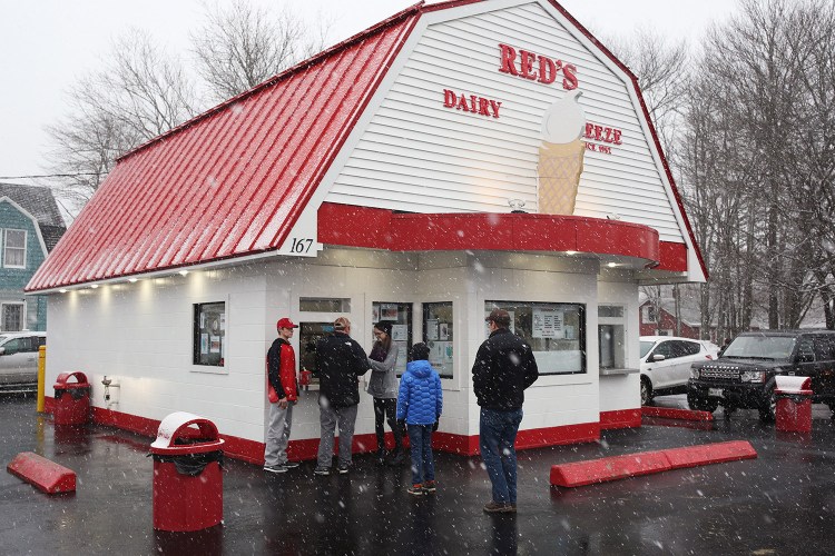 People brave an oncoming winter storm to line up outside Red's Dairy Freeze as the ice cream shop opened for the 2018 season on March 7. The 2019 season started Monday.