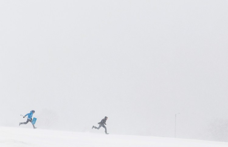 Two people run through the heavy snow in Eastern Prom park in Portland during Tuesday's nor'easter.