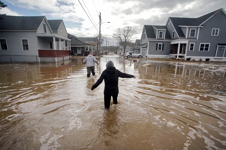 Kaylee Collin, right, and Spencer Stone walk through water along North Avenue in Camp Ellis in Saco on Sunday, March 4. The coastal neighborhood as well as other parts of the southern Maine coast were flooded for the third day in a row on Sunday. 