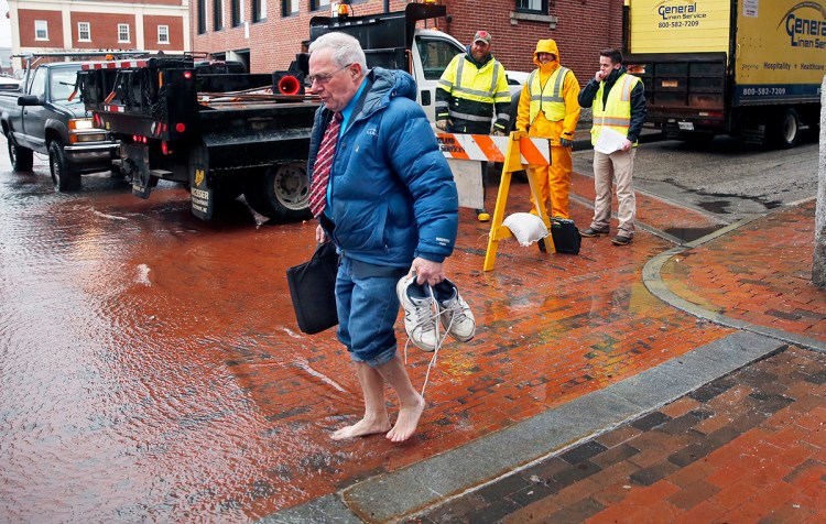 Lawyer Fred Moore prepares to enter floodwater on Portland Pier on March 2 while city employees Brian Cogill, Ryan Sullivan and Kevin Deneault look on. High winds and rain coincided with a lunar high tide, which pushed seawater against the door of Moore's office at Robinson, Kriger & McCallum. 