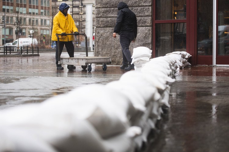 Workers place sandbags in front of the entrance to Faneuil Hall to prevent further flooding during the storm in Boston on Friday. 