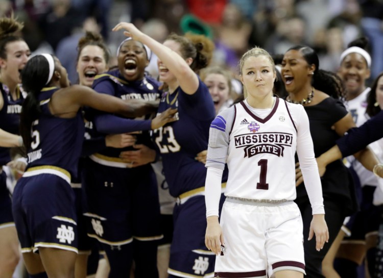 Notre Dame's Arike Ogunbowale is congratulated by teammates as Mississippi State's Blair Schaefer (1) walks away after Ogunbowale made a 3-point basket to defeat Mississippi State 61-58 in the final of the women's NCAA Final Four college basketball tournament, Sunday, April 1, 2018, in Columbus, Ohio. (AP Photo/Tony Dejak)