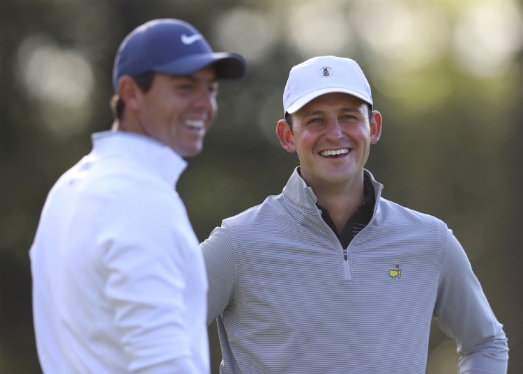 Matt Parziale, right, the U.S. Mid-Amateur champion who works as a firefighter in Brockton, Massachusetts, shares a laugh with Rory McIlroy during a practice round for the Masters golf tournament Monday in Augusta, Georgia. (Curtis Compton/Atlanta Journal-Constitution via AP)
