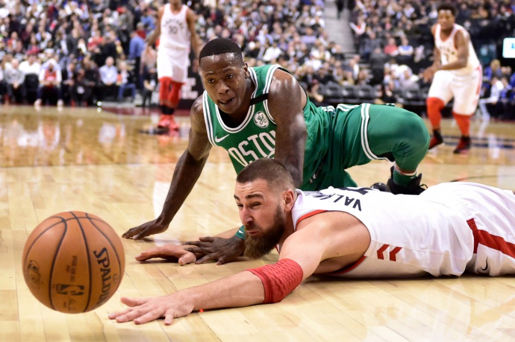 Toronto's Jonas Valanciunas and Boston's Terry Rozier fall to the floor chasing a loose ball in the second half Wednesday at Toronto.