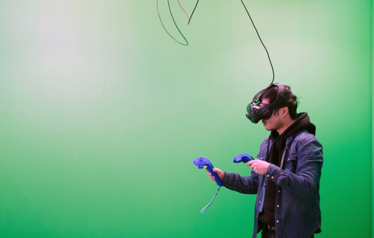 A customer wears a HTC Vive virtual-reality headset during a green-screen experience at Toronto's House of VR. Despite Hollywood funding and top industry talent, cinematic VR has yet to yield commercial success or popular acceptance.